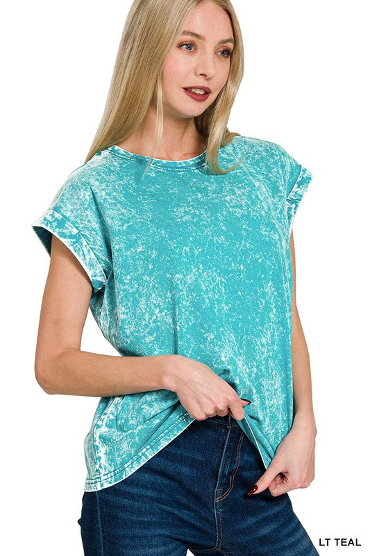 Woman wearing a light teal distressed t-shirt and blue jeans on a white background